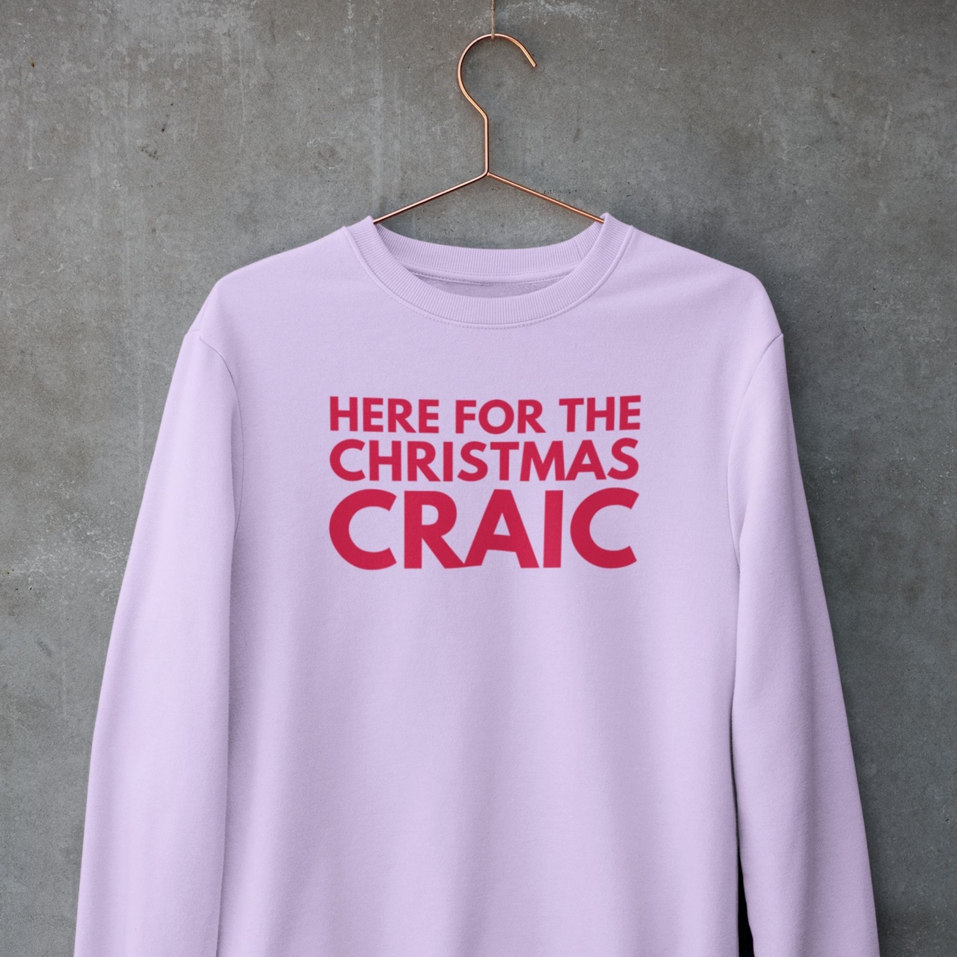 Pink sweatshirt with red text 'HERE FOR THE CHRISTMAS CRAIC' on a hanger