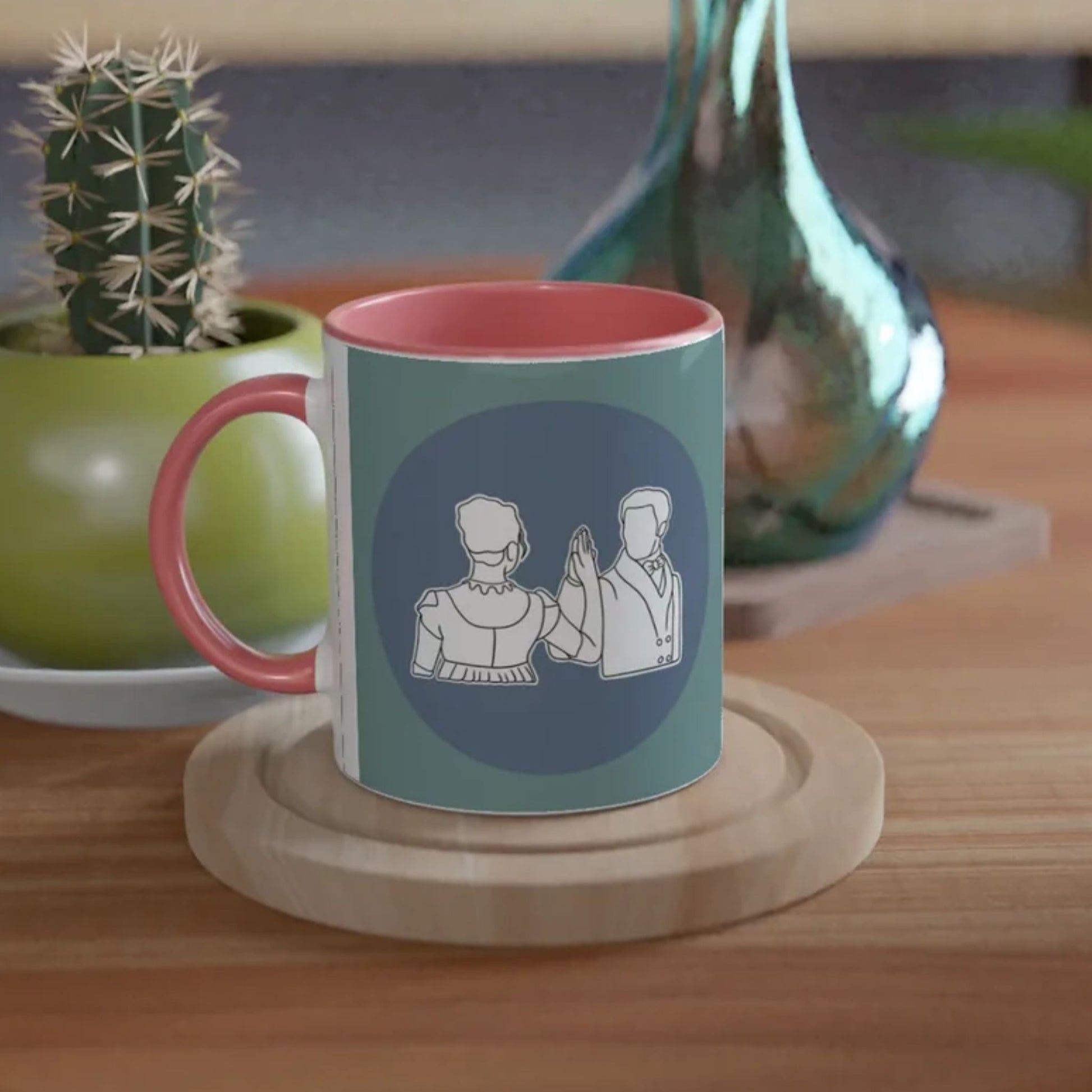 Jane Austen inspired mug with a design of Mr Darcy and Elizabeth Bennett dancing on a wooden coaster with a plant and vase in the background.