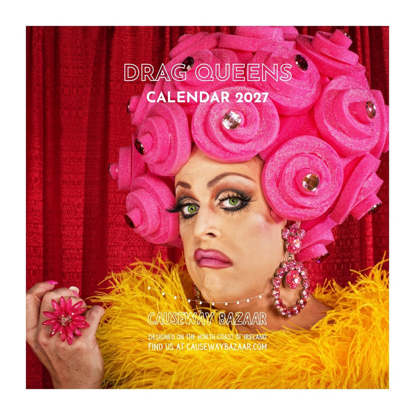 A square promotional image for the 'Drag Queens Calendar 2027' by Causeway Bazaar, featuring a close-up portrait of a drag queen with a large pink hairpiece, red curtain background, and yellow feather boa. The text 'DRAG QUEENS CALENDAR 2027' and 'CAUSEWAY BAZAAR' are visible.