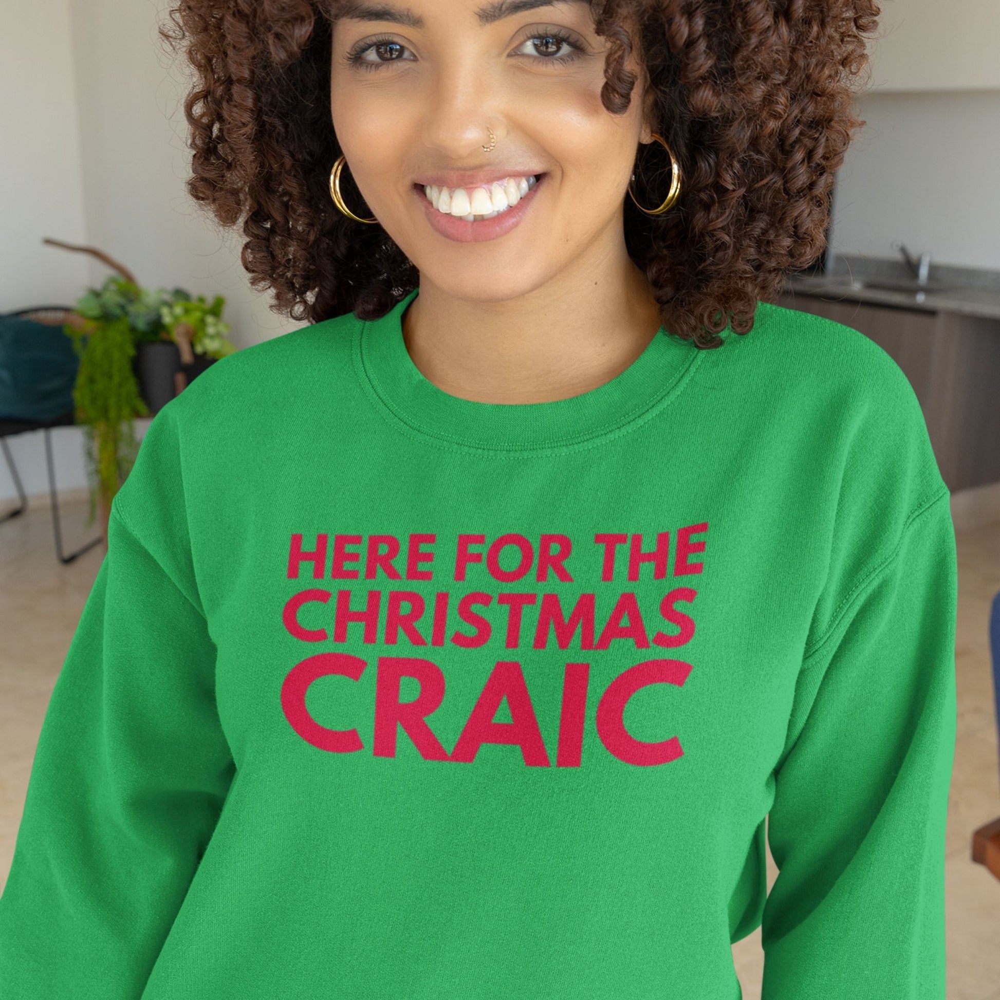 Person wearing a green sweatshirt with red text in a kitchen setting