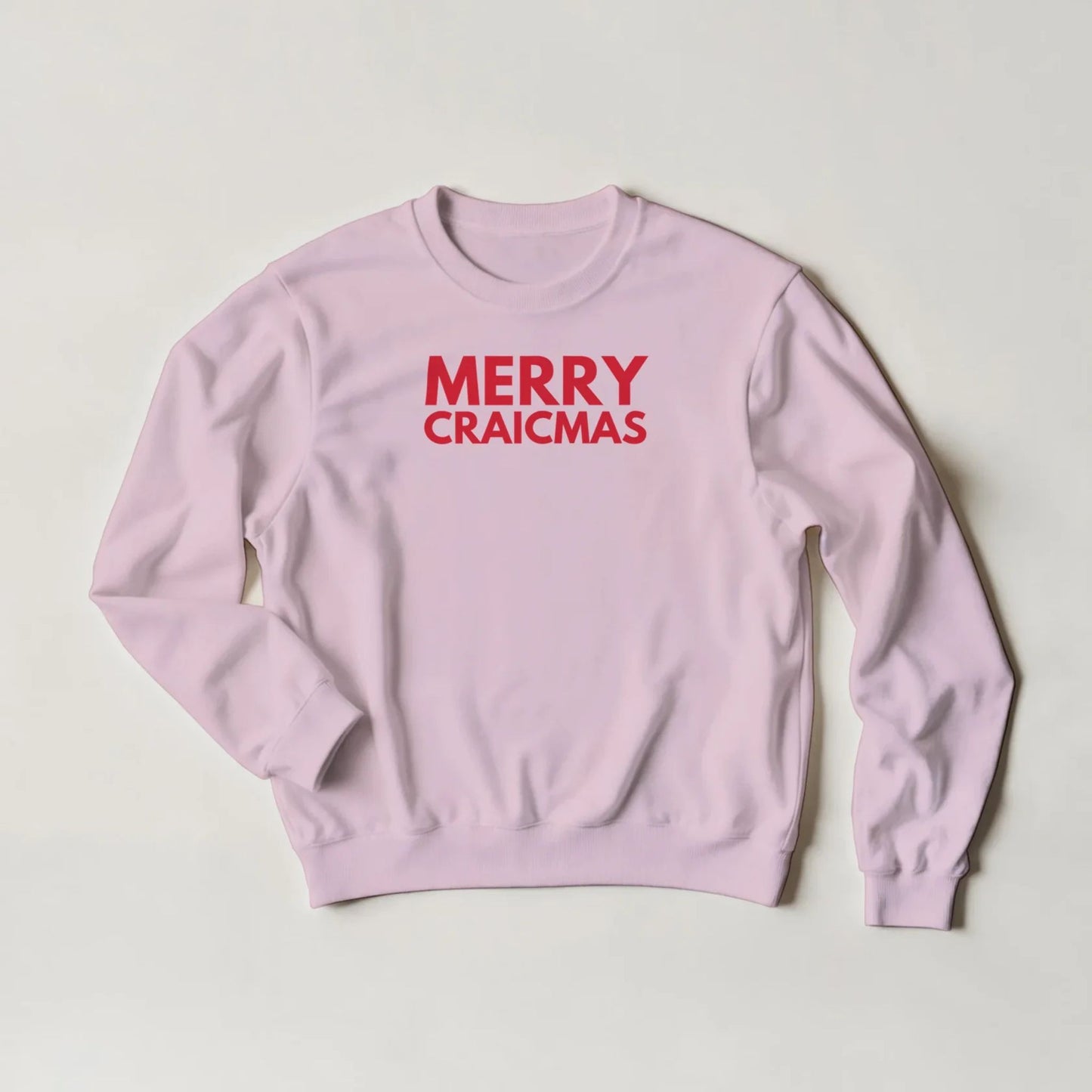 Pink sweatshirt with 'MERRY CRAICMAS' red text on a light grey background