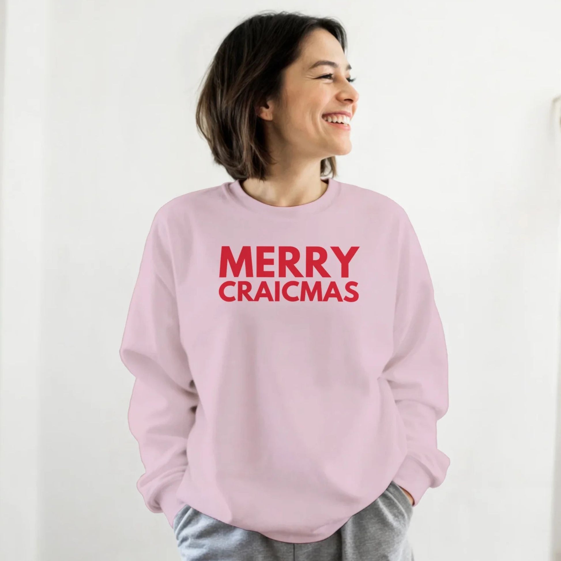 Person wearing a pink sweatshirt with 'MERRY CRAICMAS' red text on a white background