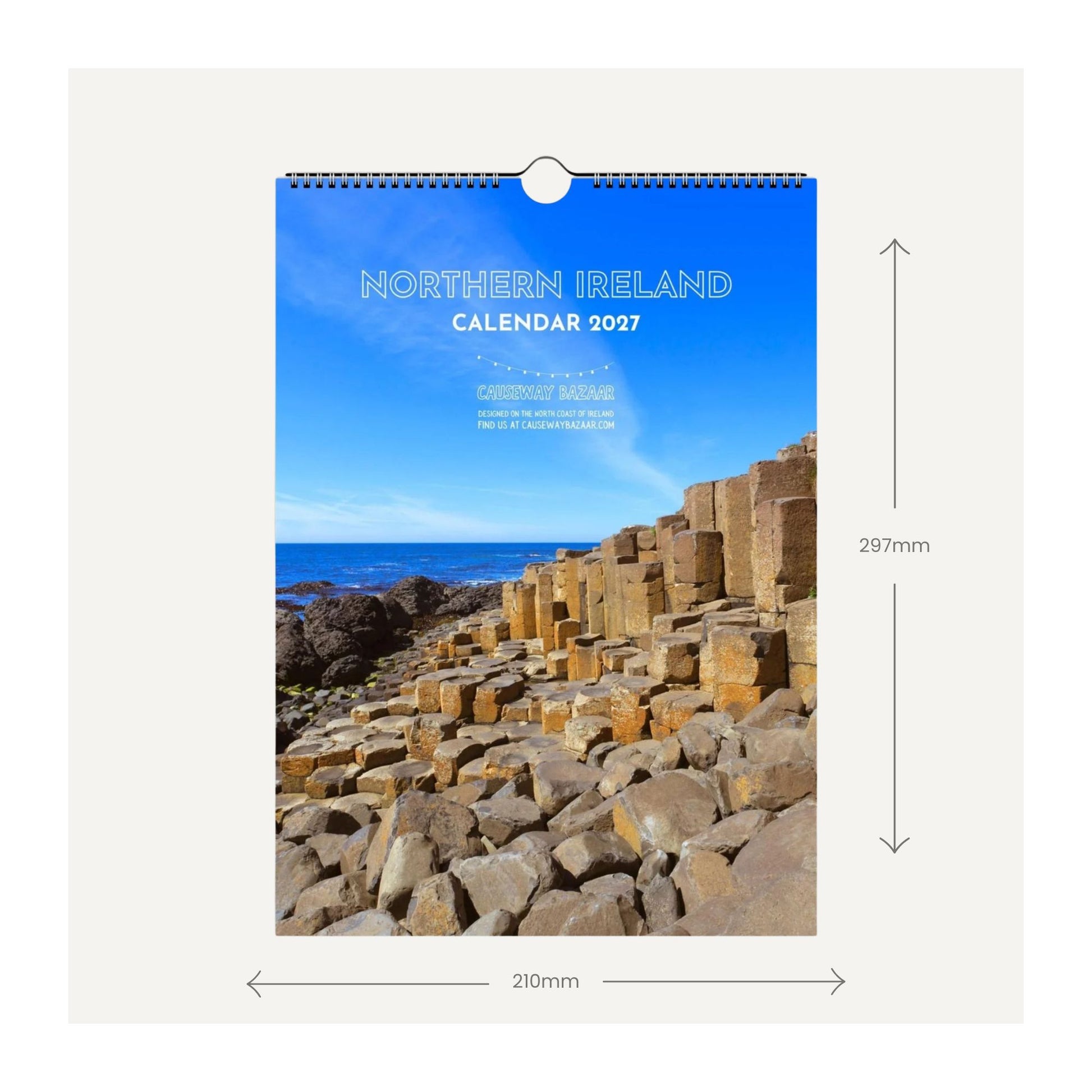 Northern Ireland 2037 wall calendar shown hanging against a light gray background, with dimension arrows indicating 297mm height and 210mm width. The cover features a blue sky and the Giant's Causeway rock formations.