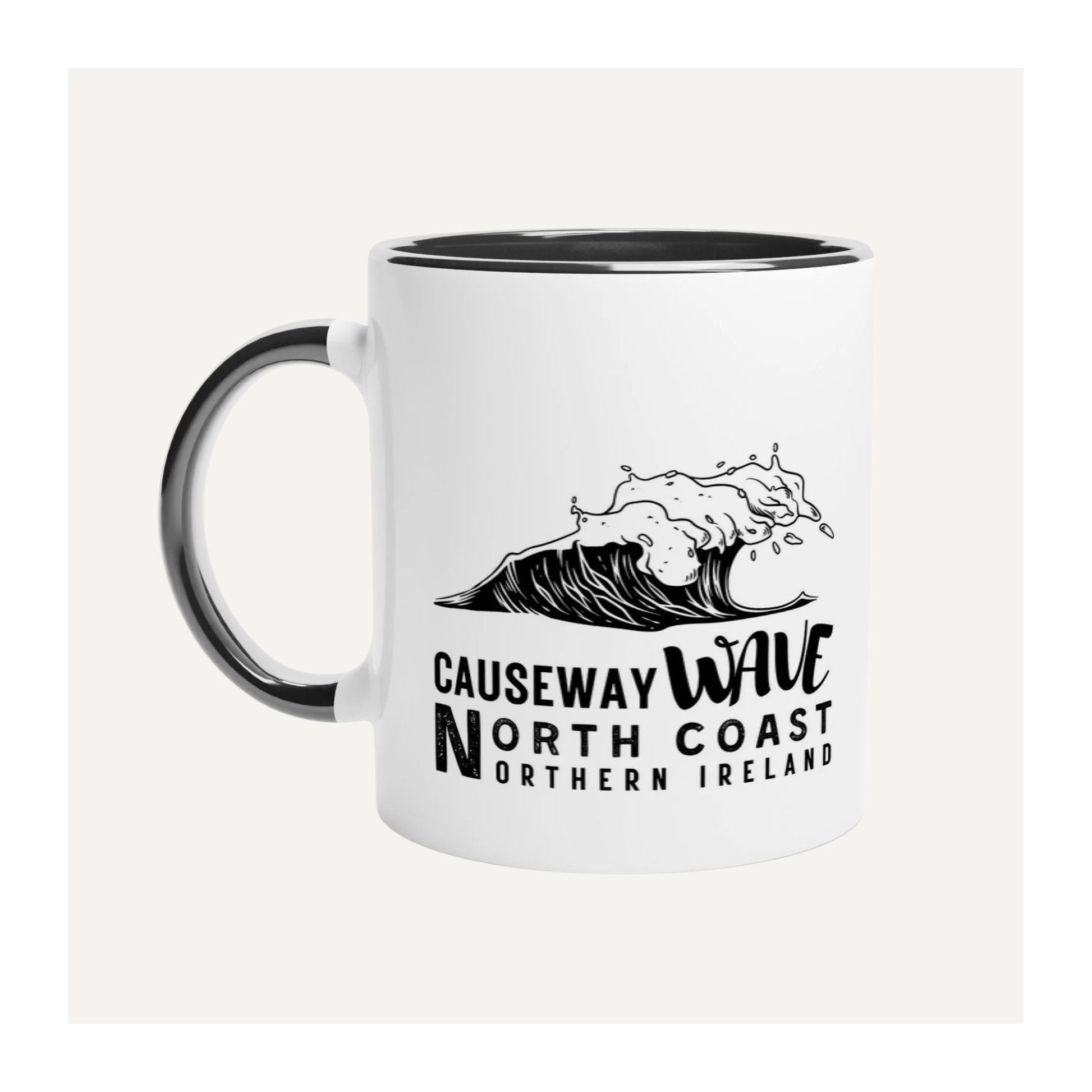 White mug with black handle featuring a wave design and Causeway Wave North Coast Northern Ireland text on a white background