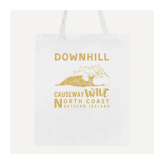 White tote bag with gold text 'Downhill Causeway Wave North Coast Northern Ireland' and wave design on a white background