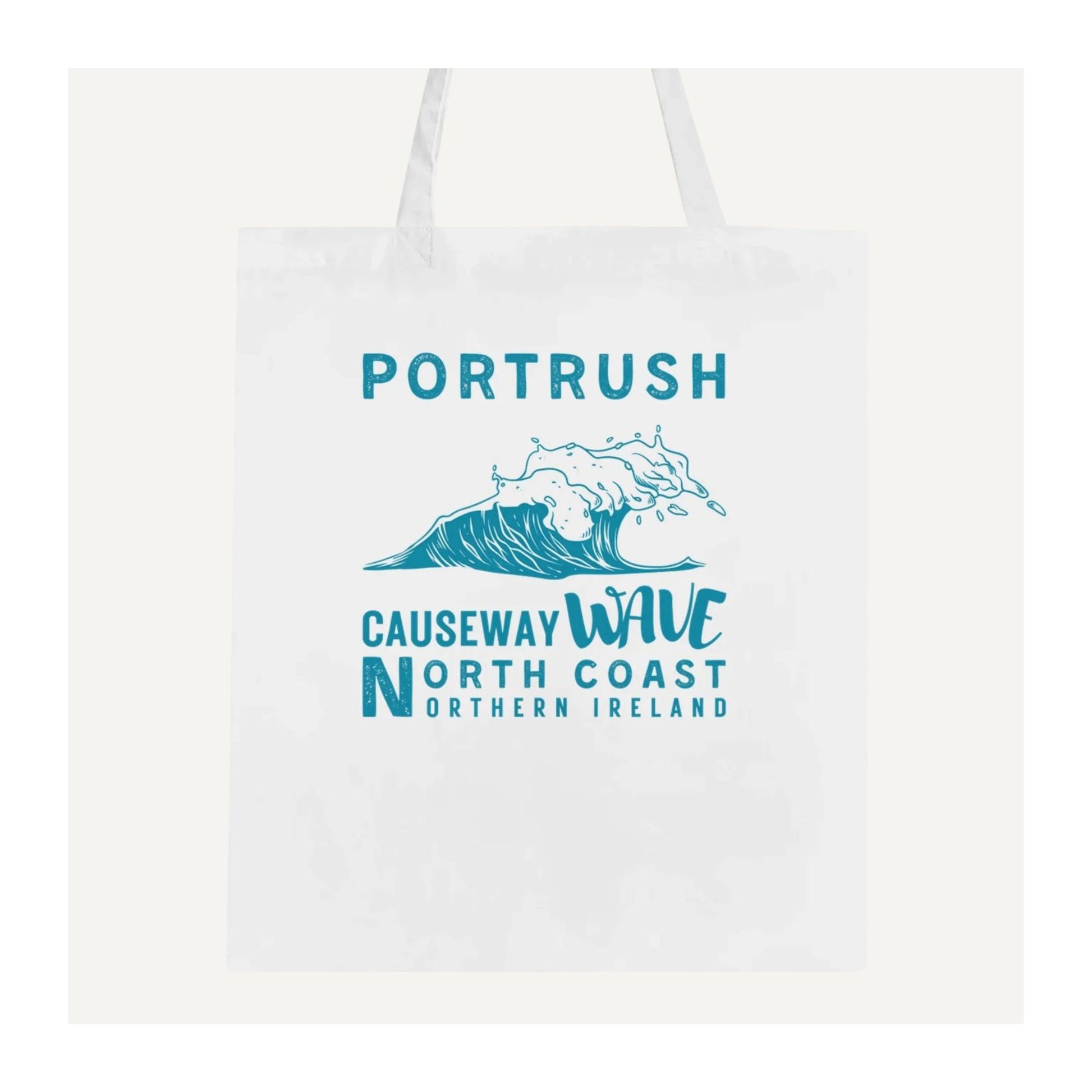 White tote bag with blue text 'Portrush Causeway Wave North Coast Northern Ireland' and wave graphic on a white background