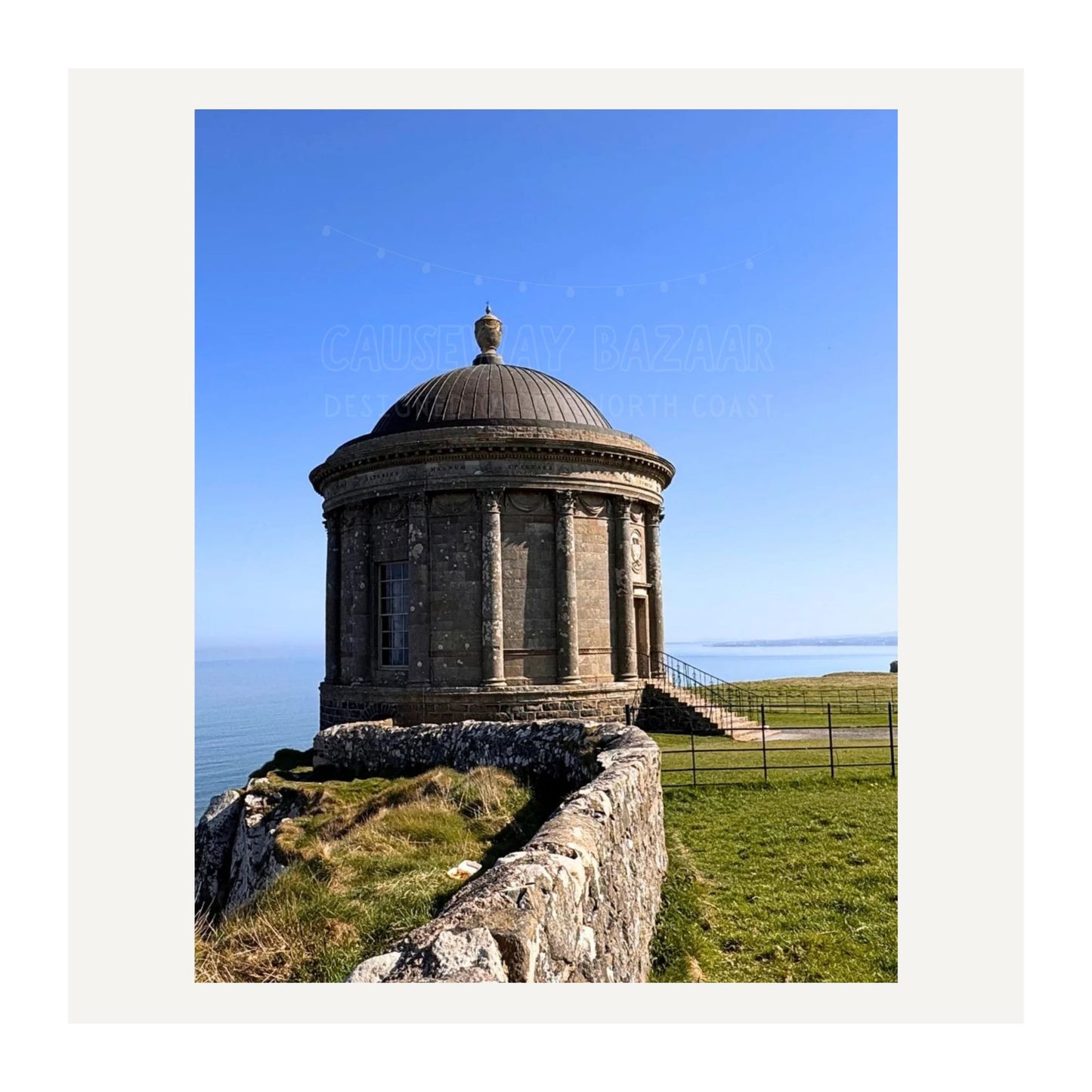 Mussenden Temple round stone building perched on a clifftop at Benone on the North Coast with clear blue sky. Image depicts Art print available for sale.