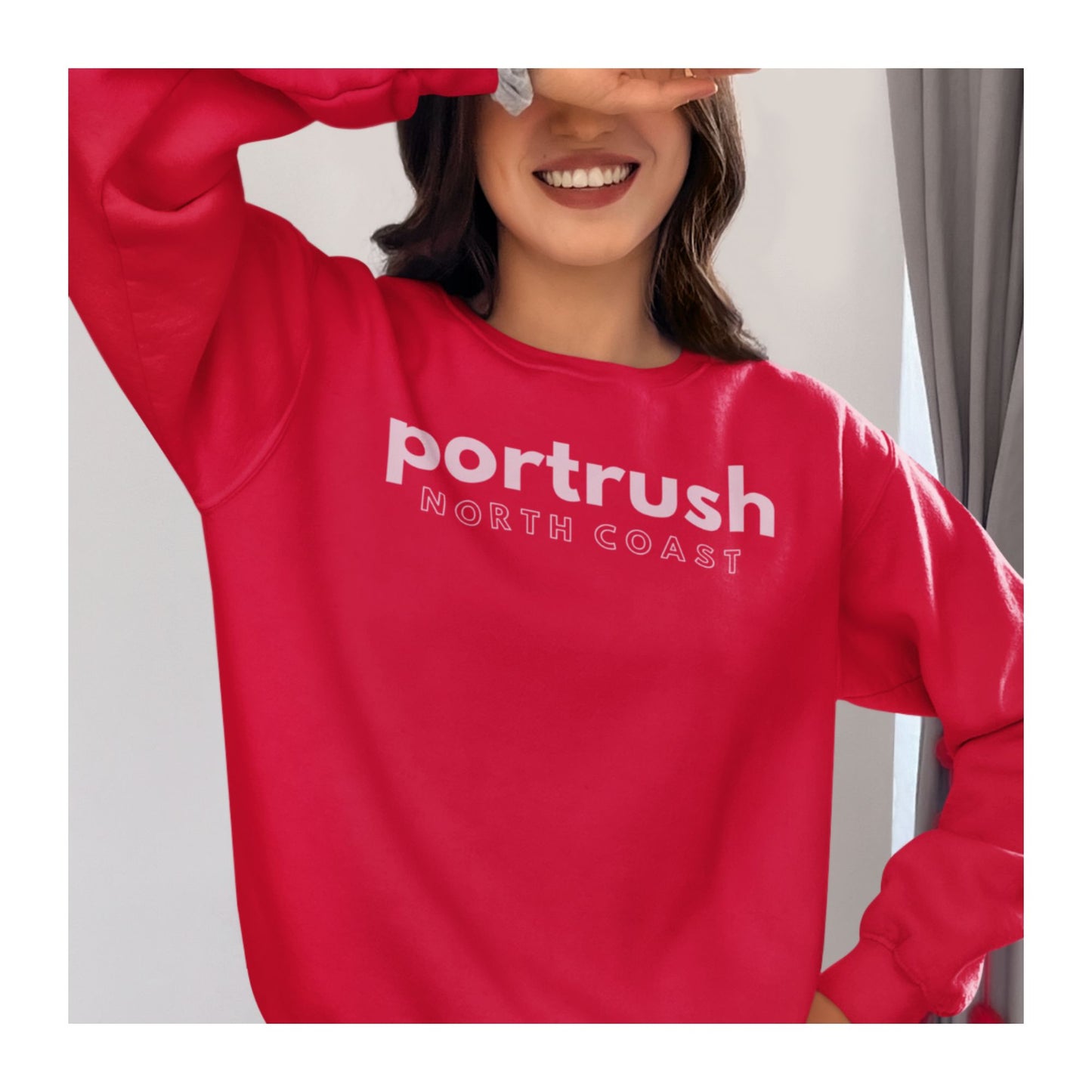 Model wearing Northern Ireland Red sweatshirt with 'Portrush North Coast' in pink text 
