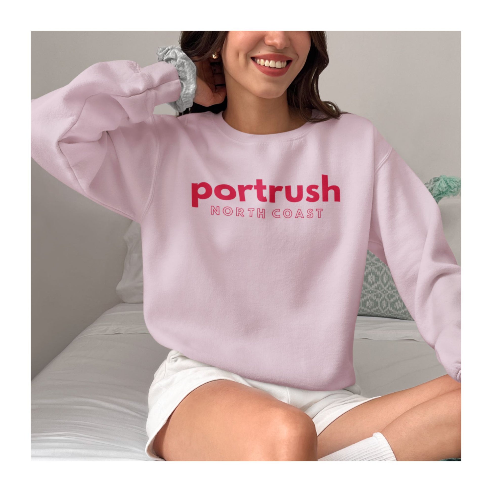 Model wearing Northern Ireland Pink sweatshirt with 'Portrush North Coast' in red text 