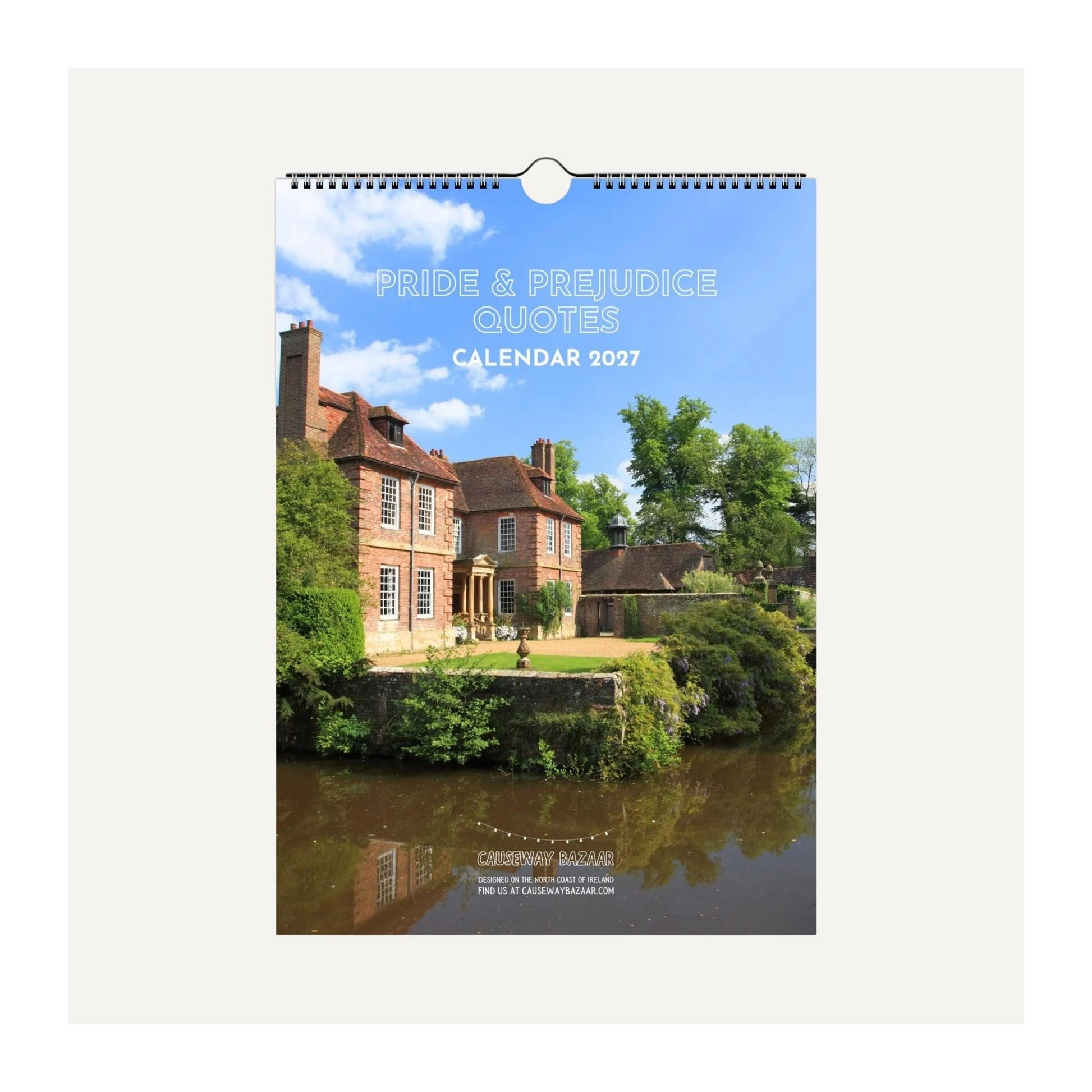 A hanging wall calendar cover shown flat against a light gray background. The cover features a scenic photograph of a brick house beside a river, with the text 'PRIDE & PREJUDICE QUOTES CALENDAR 2027' at the top.